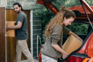 man and woman carrying moving boxes