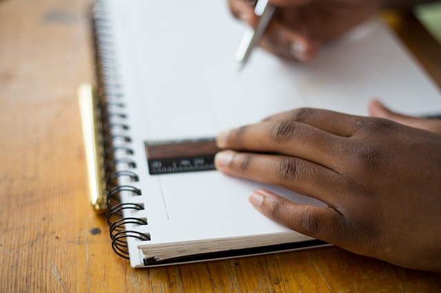 person drawing in notebook using ruler