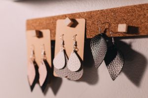 white, black, and pink earrings shown hanging from a corkboard