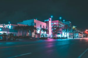 Building lit up in miami at night and surrounded by palm trees