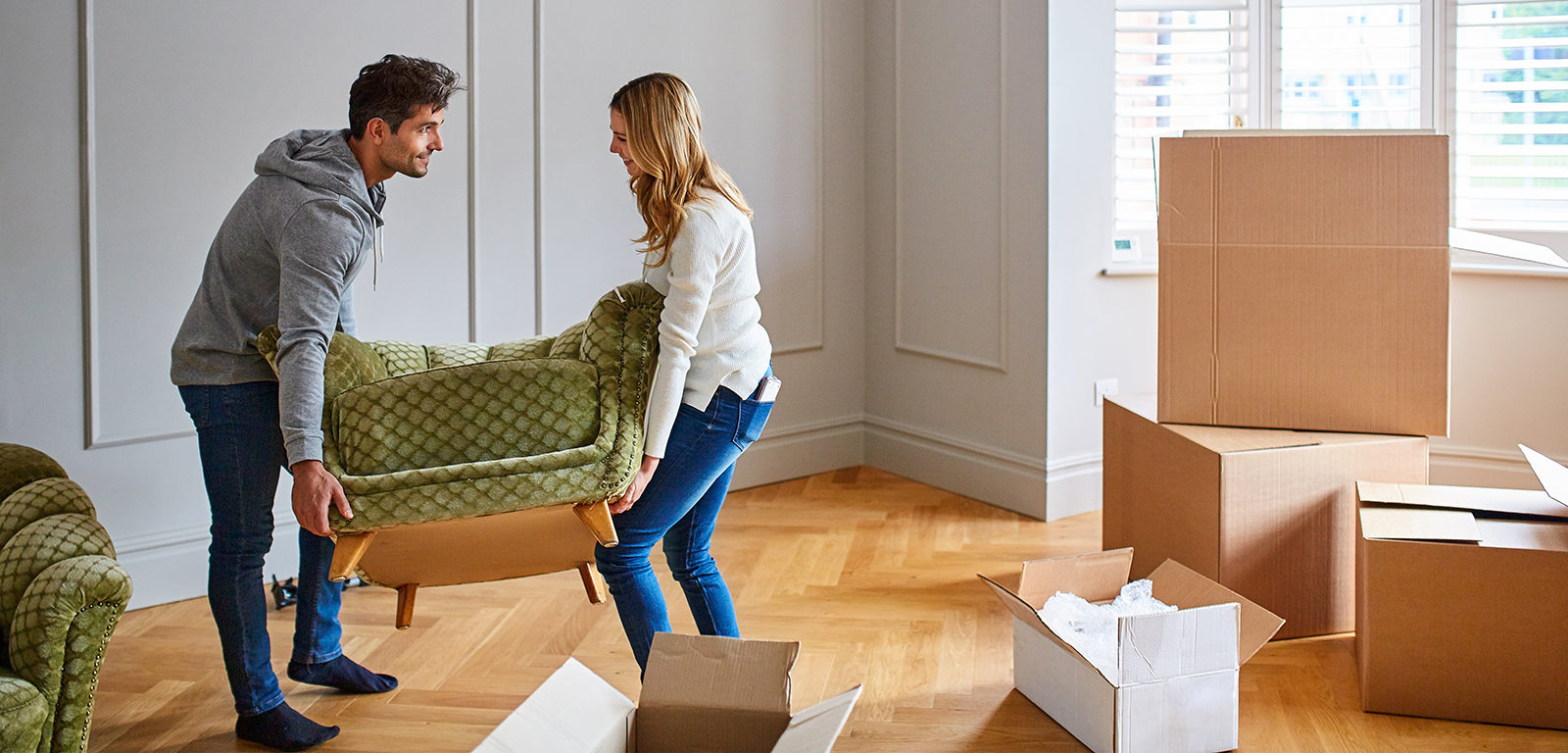 A coupe moving a couch together in their new home